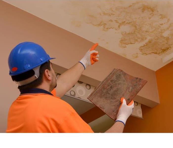 a man pointing at water damage on a ceiling 
