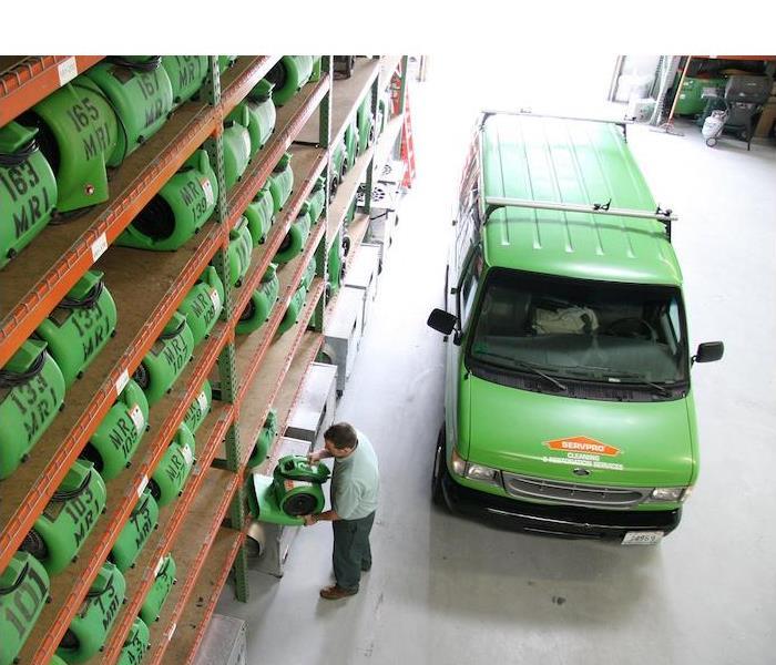 < img sra green SERVPRO van parked in a warehouse full of equipment